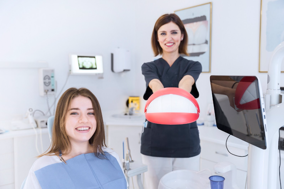 A smiling female patient in front of her dentist