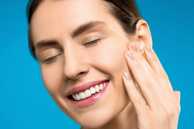 A woman with a beautiful smile touching her cheeks after restorative
dental work