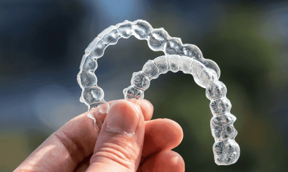 A Man Holding Invisalign Aligners for sleep apnea treatment in the Air With Fingers
