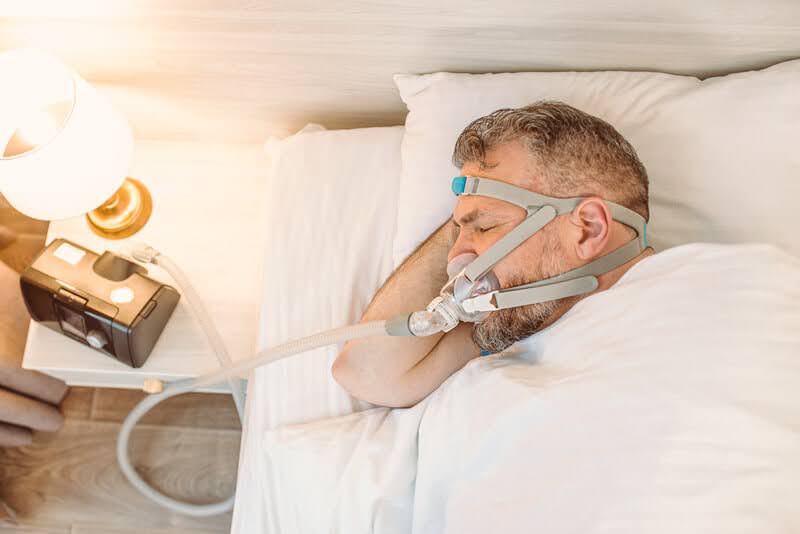  A Man Using a Sleep Apnea Treatment Machine
