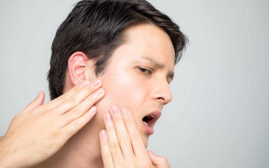 A Man Curiously Running His Fingers Over the Jaw Pain A Man Curiously Running His Fingers Over the Jaw Pain